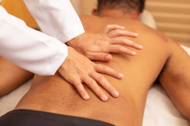 Birkaç vakum kabı izi olan bir hastanın sırtına masaj yapan terapist..