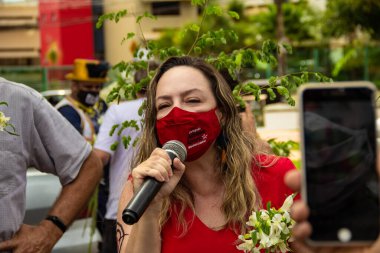 Kırmızı maske takan ve mikrofona konuşan eski belediye başkanı adayı Bolsonaro Adriana Accorsi 'nin görevden alınması için gösteri çağrısı.