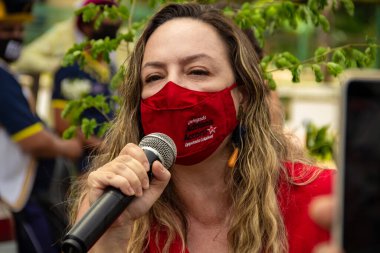 Kırmızı maske takan ve mikrofona konuşan eski belediye başkanı adayı Bolsonaro Adriana Accorsi 'nin görevden alınması için gösteri çağrısı.