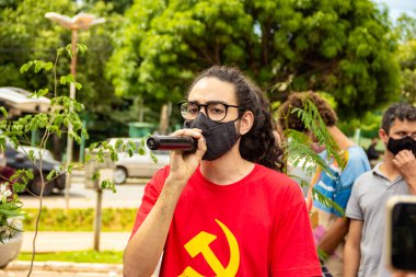 Kırmızı bluzlu ve siyah maskeli çocuk protestoda mikrofona konuşuyor. Brezilya Başkanı 'nın görevden alınmasını talep ediyor..
