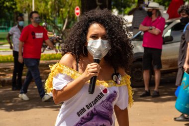 Protesto sırasında mikrofona konuşan maskeli kadın Brezilya başkanının görevden alınmasını istiyor..