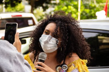 Başkan Bolsonaro 'nun görevden alınmasını talep eden bir protestoda maskeli bir kadın sorguya çekiliyor..