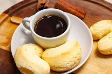  Tahta bir tahtanın üzerinde peynirli bisküvi ve tarçın parçalarıyla bir fincan kahve..