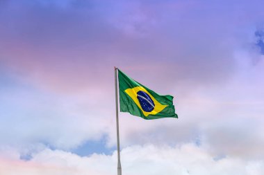 Flag of Brazil, raised and waving in the wind with sky in the background. clipart