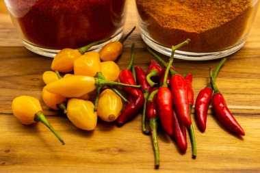 Ahşap yüzeyde kırmızı ve sarı biberler ve safran ve kırmızı biber bardakları..