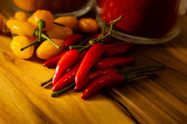 Ahşap yüzeyde kırmızı ve sarı biberler ve safran ve kırmızı biber bardakları..