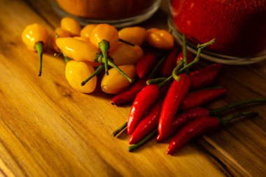 Ahşap yüzeyde kırmızı ve sarı biberler ve safran ve kırmızı biber bardakları..