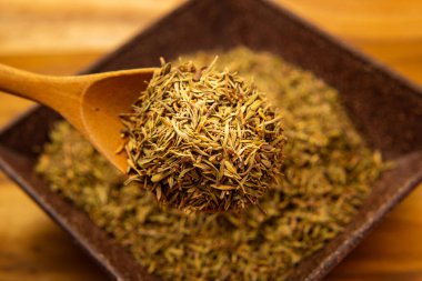 Bir kaşık dolusu kuru kekik dipteki bir kaseye dökülüyor..