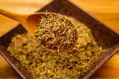 Bir kaşık dolusu kuru kekik dipteki bir kaseye dökülüyor..