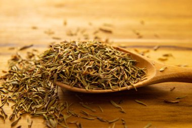 Masanın üzerinde kurumuş kekik dolu tahta bir kaşık..