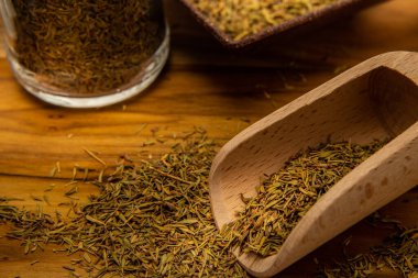 Kereste dolu kalın tahta kaşık, bardak ve kase. Kekik masaya döküldü..