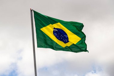 Brezilya bayrağı; Arkasında bulutlu gökyüzü olan direkte Brezilya bayrağı.