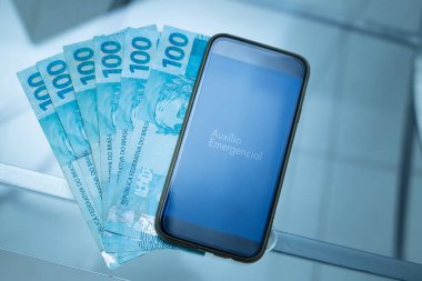 Acil yardım uygulamalı cep telefonu ve 100 reais fatura. Karantina süresince Brezilya hükümetinden yardım.
