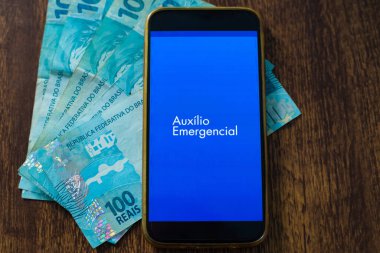 Acil yardım uygulamalı cep telefonu ve 100 reais fatura. Karantina süresince Brezilya hükümetinden yardım.