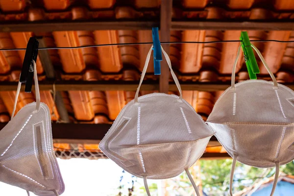 Three white face protection masks. Three face masks for protection against disease contagion, hanging from the clothesline for disinfection.