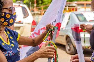 Goinia şehrinde kültürel profesyonellerin gösterisi için bayrak direğine renkli kurdele bağlayan iki genç kadın..