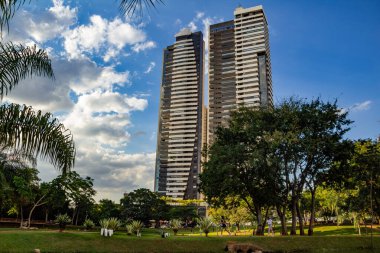 Bazı binalarla, ağaçlarla ve arkasında bulutlar olan mavi gökyüzüyle manzara. Fotoğraf Flamboyant Park 'ta çekildi..
