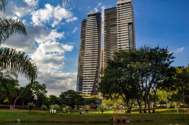Bazı binalarla, ağaçlarla ve arkasında bulutlar olan mavi gökyüzüyle manzara. Fotoğraf Flamboyant Park 'ta çekildi..