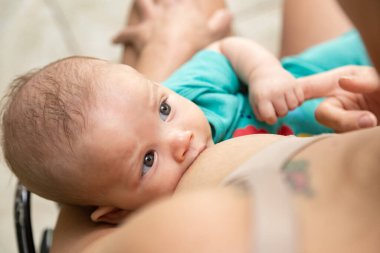 Bir bebek emziriyor ve annesinin elini tutuyor. Annelik kavramı.