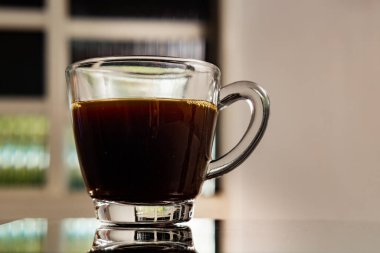 Yansıtıcı yüzeyinde kahve olan berrak bir cam bardak..