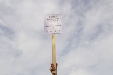 Tabela tutan kişi. Fotoğraf, Brezilya Başkanı Bolsonaro 'ya karşı yapılan bir protesto sırasında çekildi ve nüfusu aşılamak için aşı satın almada çeviklik talep ediliyor..