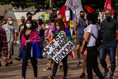 Protestocular gösteride maske takıp tabela tutuyorlar. Protesto; Brezilya Cumhurbaşkanı Bolsonaro 'ya karşı düzenlenen bir protesto sırasında çekilen fotoğraf ve nüfusu bağışık hale getirmek için aşı satın almada çeviklik istenmesi.