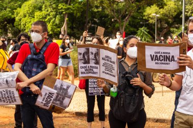 Protestocular gösteride maske takıp tabela tutuyorlar. Protesto; Brezilya Cumhurbaşkanı Bolsonaro 'ya karşı düzenlenen bir protesto sırasında çekilen fotoğraf ve nüfusu bağışık hale getirmek için aşı satın almada çeviklik istenmesi.