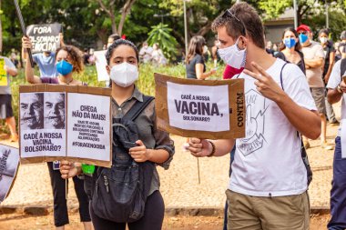 Protestocular gösteride maske takıp tabela tutuyorlar. Protesto; Brezilya Cumhurbaşkanı Bolsonaro 'ya karşı düzenlenen bir protesto sırasında çekilen fotoğraf ve nüfusu bağışık hale getirmek için aşı satın almada çeviklik istenmesi.