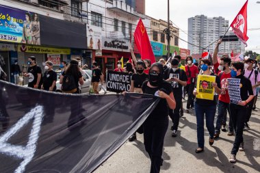 Protestocular gösteride maske takıp tabela tutuyorlar. Protesto; Brezilya Cumhurbaşkanı Bolsonaro 'ya karşı düzenlenen bir protesto sırasında çekilen fotoğraf ve nüfusu bağışık hale getirmek için aşı satın almada çeviklik istenmesi.