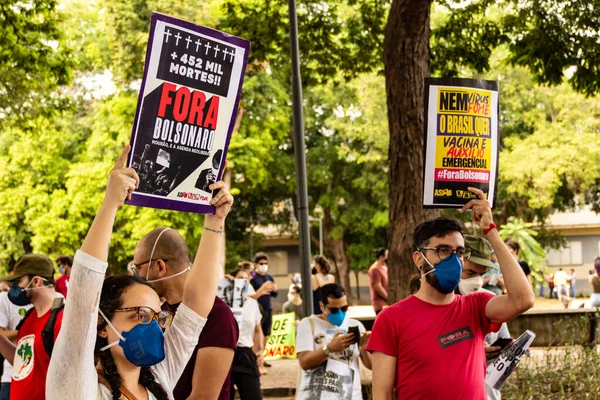Protestoda iki protestocu bir tabela tutuyor. Protesto; Brezilya Cumhurbaşkanı Bolsonaro 'ya karşı düzenlenen bir protesto sırasında çekilen fotoğraf ve nüfusu bağışık hale getirmek için aşı satın almada çeviklik istenmesi. 