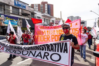 Koruyucu maskeler takan ve pankart ve posterler taşıyan protestocular. Protesto; Brezilya Cumhurbaşkanı Bolsonaro 'ya karşı düzenlenen bir protesto sırasında çekilen fotoğraf ve nüfusu bağışık hale getirmek için aşı satın almada çeviklik istenmesi.