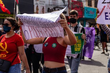 Elinde tabela tutan maskeli bir protestocu. Fotoğraf, Brezilya Başkanı Bolsonaro 'ya karşı yapılan bir protesto sırasında çekildi ve nüfusu aşılamak için aşı satın almada çeviklik talep ediliyor..