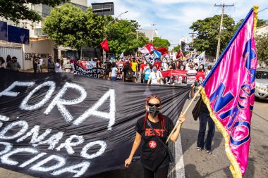 Protestocular ellerinde pankart, poster ve bayraklar tutan maskeler takıyorlar. Protesto; Brezilya Cumhurbaşkanı Bolsonaro 'ya karşı düzenlenen bir protesto sırasında çekilen fotoğraf ve nüfusu bağışık hale getirmek için aşı satın almada çeviklik istenmesi.