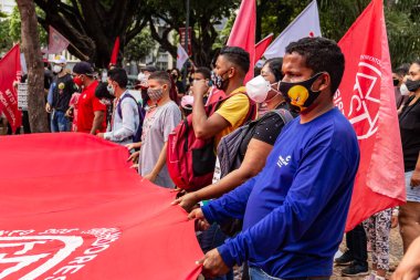 Protestocular ellerinde pankart, poster ve bayraklar tutan maskeler takıyorlar. Protesto; Brezilya Cumhurbaşkanı Bolsonaro 'ya karşı düzenlenen bir protesto sırasında çekilen fotoğraf ve nüfusu bağışık hale getirmek için aşı satın almada çeviklik istenmesi.