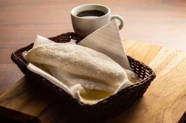 Masada bir fincan kahveyle küçük bir sepetin içine tıkıştırılmış iki tapyoka. Tapyoka - nişastandan yapılmış tipik Brezilya yemeği.