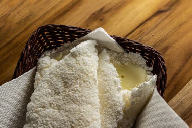 Tahta bir masada küçük bir hasır sepetin içinde iki tapyoka. Tapyoka - nişastandan yapılmış tipik Brezilya yemeği.