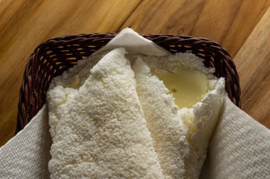 Tahta bir masada küçük bir hasır sepetin içinde iki tapyoka. Tapyoka - nişastandan yapılmış tipik Brezilya yemeği.