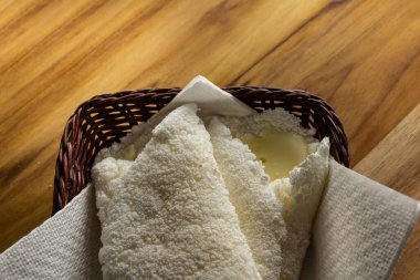 Tahta bir masada küçük bir hasır sepetin içinde iki tapyoka. Tapyoka - nişastandan yapılmış tipik Brezilya yemeği.