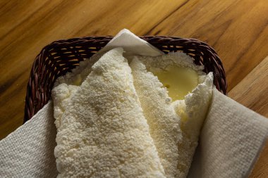 Tahta bir masada küçük bir hasır sepetin içinde iki tapyoka. Tapyoka - nişastandan yapılmış tipik Brezilya yemeği.