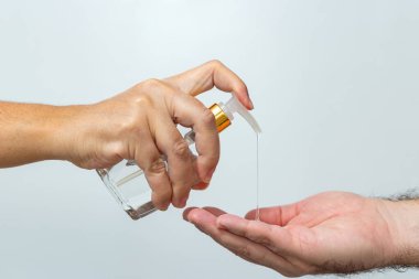 Alkol bazlı antiseptik jel kullanan insanlar. Bir kadın, bir erkeğin ellerini dezenfektanla yıkar..