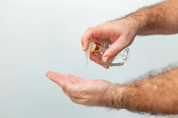 Hands of a man who is sanitizing himself with alcohol. Hand hygiene recommendations during the Covid 19 pandemic restriction. Hands of a man taking hand sanitizer alcohol gel to clean his hand.