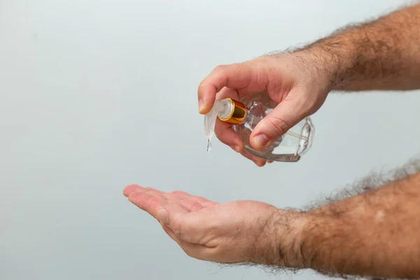 Hands of a man who is sanitizing himself with alcohol. Hand hygiene recommendations during the Covid 19 pandemic restriction. Hands of a man taking hand sanitizer alcohol gel to clean his hand.