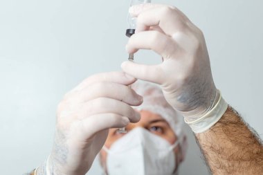 Bir doktor şırıngayı ilaçla hazırlıyor. Şırınga ile covid-19 aşısı.