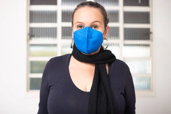 A woman with hair up, scarf and mask in blue color.