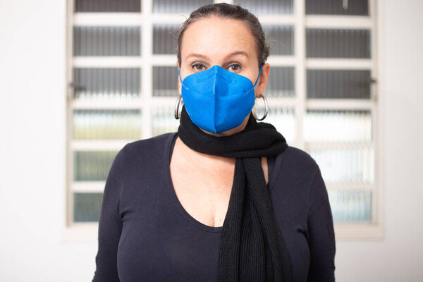  A woman with hair up, scarf and mask in blue color.