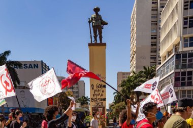 Goiania 'daki Bandeirante meydanının önünden geçen posterleri ve bayrakları olan protestocular. Brezilya cumhurbaşkanı Jair Bolsonaro 'ya karşı protesto.