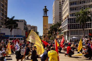 Goiania 'daki Bandeirante meydanının önünden geçen posterleri ve bayrakları olan protestocular. Brezilya cumhurbaşkanı Jair Bolsonaro 'ya karşı protesto.