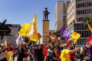 Goiania 'daki Bandeirante meydanının önünden geçen posterleri ve bayrakları olan protestocular. Brezilya cumhurbaşkanı Jair Bolsonaro 'ya karşı protesto.
