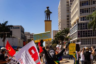 Goiania 'daki Bandeirante meydanının önünden geçen posterleri ve bayrakları olan protestocular. Brezilya cumhurbaşkanı Jair Bolsonaro 'ya karşı protesto.