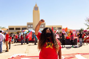 Koruyucu maske takan bir aktivist, Goinia 'daki İşçi Meydanı' nda bir protestoda, arkasında Frei Confaloni Müzesi ile. 24J.